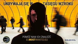 Plakat, na którym widnieje sylwetka osoby z zaciemnioną twarzą. Za sylwetka widoczne są rozmyte sylwetki innych osób. W górnej części plakatu widnieje napis ukrywają się w zasięgu wzroku, na dole pomóż nam ich znaleźć eumostwanted.eu, z prawej i lewej strony znajduje się logo Europolu i Enfast.