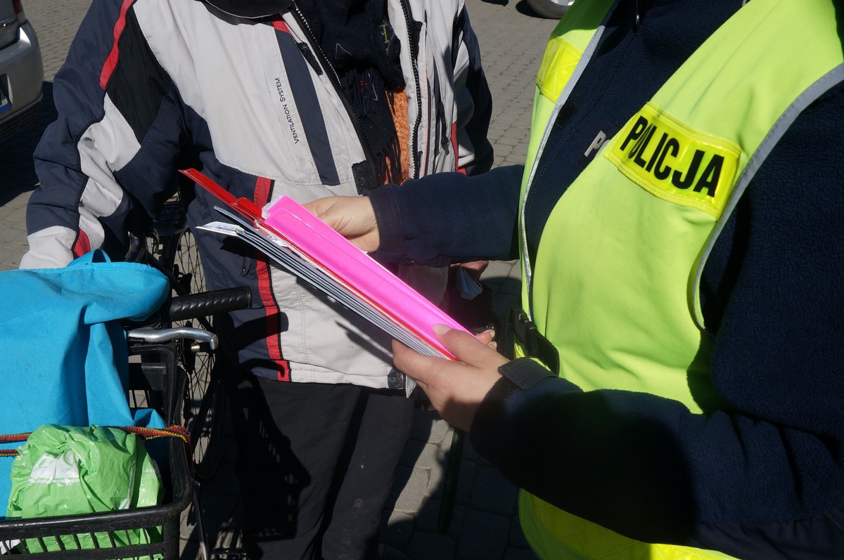 fragment policjantki i rowerzysty któremu wrecza odblask
