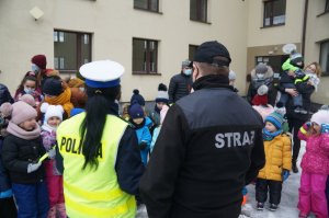 policjantka i strażak stoją tyłem w tle dzieci
