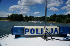 fragment policyjnej motorówki widoczny napis policjaq w tle jezioro i plaża