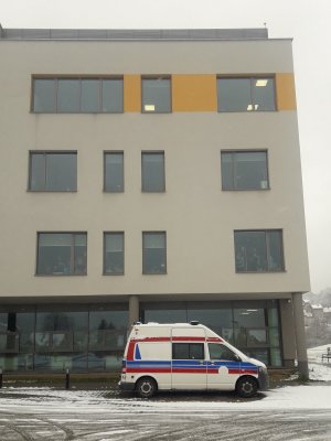 budynek szpitala pod którym stoi karetka w oknach widoczne dzieci