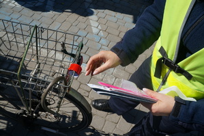 fragment policjantki oraz kosza na rower na którym założony jest odblask