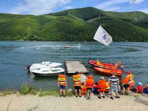 dzieci stoją na brzegu jeziora motorówki pływają na jeziorze
