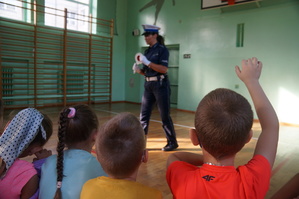 policjantka w czasie prelekcji przodem do uczniów na pierwszym planie uczeń który zgłasza się do odpowiedzi