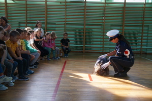 policjantka wykonuje ćwiczenie praktyczne z uczniem pozostali uczniowie siedzą w ławce