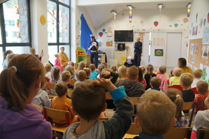 dzieci siedzą tyłem policjantka na środku sali prowadzi prelekcje