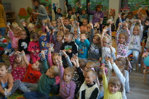 dzieci trzymają do góry ręce w których mają zawieszki odblaskowe