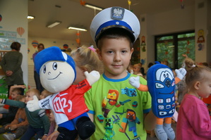 chłopczyk trzyma maskotki w ręce na głowie ma policyjna czapkę