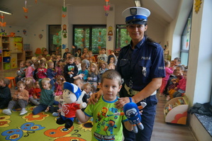 policjantka stoi z chłopczykiem który trzyma maskotki