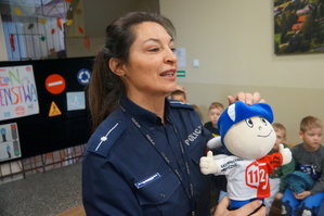 policjantka z maskotką centrum powiadamiania ratunkowego uczy dzieci numerów alarmowych
