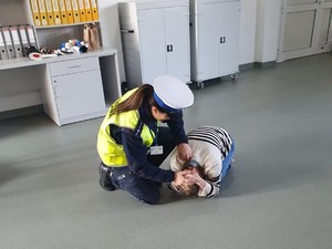policjantka wspólnie z uczniem pokazuje pozycje bezpieczną w przypadku ataku groźnego psa