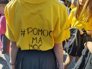 zdjęcie kolorowe dziewczyna stoi tyłem w żółtej koszulce z napisem pomoc ma moc