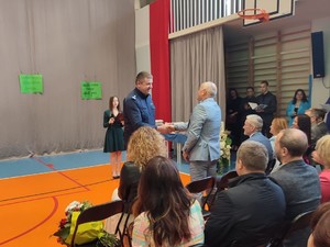 zdjęcie kolorowe zrobione na sali gimnastycznej komendant podaje rękę dyrektorowi szkoły