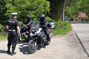 zdjęcie kolorowe policjant motocyklista stoi obok dwóch innych motocyklistów
