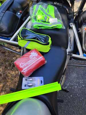 przedmioty przeznaczone dla motocyklistów kamizelki odblaski apteczka leżą na motocyklu zdjęcie kolorowe