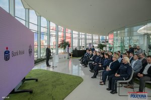 na zdjęciu osoby na krzesełkach przed ekranem