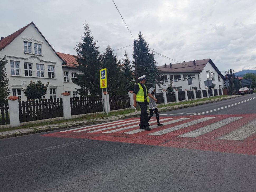 policjant przeprowadza przez przejście uczennicę