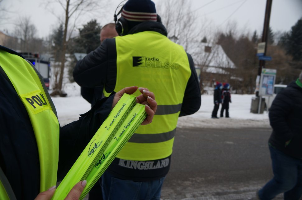 fragment policjantki która trzyma odblaski w tle redaktor i uczestnicy