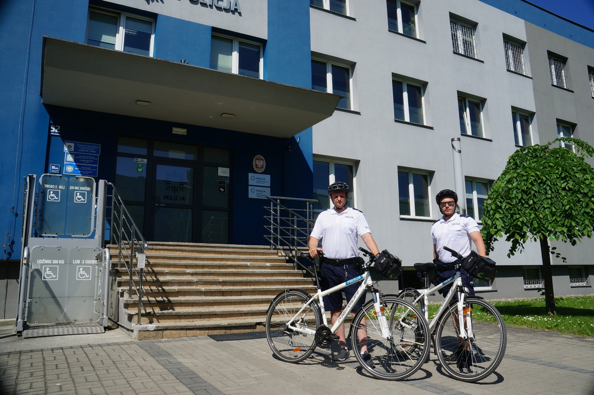 zdjęcie kolorowe przed budynkiem komendy powiatowej policji w Żywcu stoją dwaj policjanci z rowerami