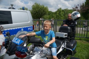 chłopczyk siedzi na motorze w tle policjant