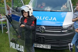 chłopczyk w policyjnym wyposażeniu na tla radiowozu
