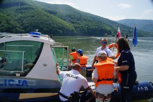 Policjanci pomagają dzieciom wejść na motorówkę