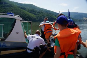 policjanci pomagają dzieciom wejść do motorówki