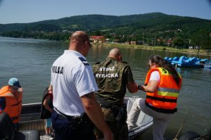 funkcjonariusz straży rybackiej pomaga dzieciom wejść na motorówkę