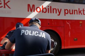ambulans do poboru krwi na pierwszym planie policjanci w czasie wypełniania nakiety