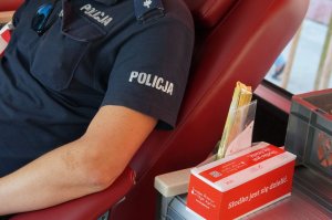 fragment ręki i koszuli z napisem policja oraz pudełka z napisem słodko jest się dzielić