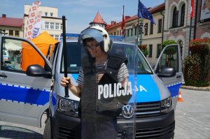 uczestnik w policyjnym wyposażeniu na tle radiowozu