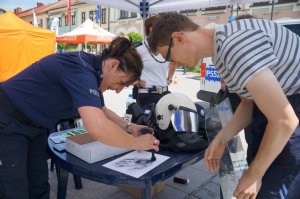 policjanci i uczestnik w czasie pobierania odcisków palców