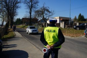 policjant stoi tyłem w tle ulica z samochodami