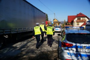 dwa radiowozy i policjanci z boku naczepa samochodu cieżarowego