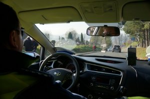 policjanci w środku radiowozu, w tel widać drogę i cmentarz