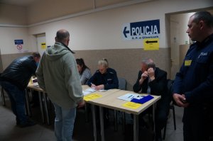 kolejny punkt kontrolny za stołem siedzą policjanci i pracownicy cywilni