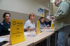 na pierwszym planie żółta tabliczka informacyjna w tle policjanci