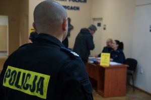 na pierwszym planie policjant tyłem z napisem policja w tle punkt kontrolny