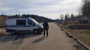 policjant stoi obok radiowozu w tle droga