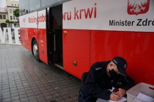 policjant siedzi przy stoliku i wypełnia formularz w tle ambulans