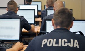 policjanci siedzą tyłem przed monitorami - zdjęcie poglądowe