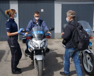 chłopak siedzi na motorze obok stoi policjantka i jego ojciec