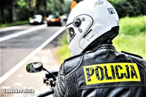 fragment policjanta na motocyklu tyłem w tle ulica