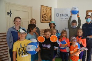 zdjęcie grupowe policjantka, opiekunka i dzieci z nagrodami