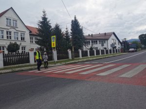 policjant przeprowadza przez drogę uczennicę