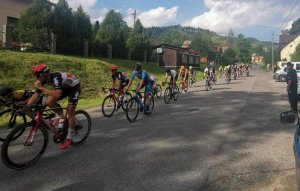 peleton kolarzy z boku stoją policjanci