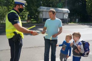 policjant wręcza mężczyźnie odblask obok stoi dwoje dzieci