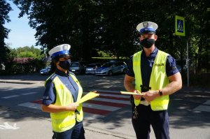 stoi policjantka z policjantem w rękach trzymają odblaski