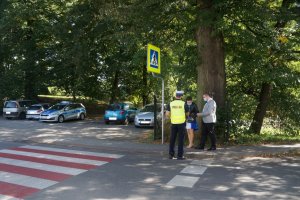 policjant wręcza kobiecie i mężczyźnie odblaski