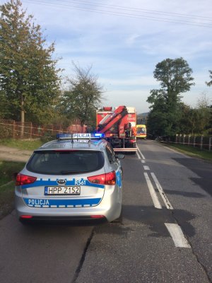 zdjęcie drogi na pierwszym planie stoi radiowóz w tle wóz strażacki oraz karetka pogotowia